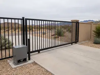 A black steel slide gate stopped halfway open across a driveway