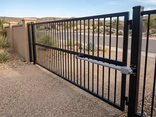 An opener arm mounted on the house side of a steel swing gate that opens inward