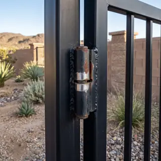 A worn gate hinge with a visible gap and shiny wear around the pin